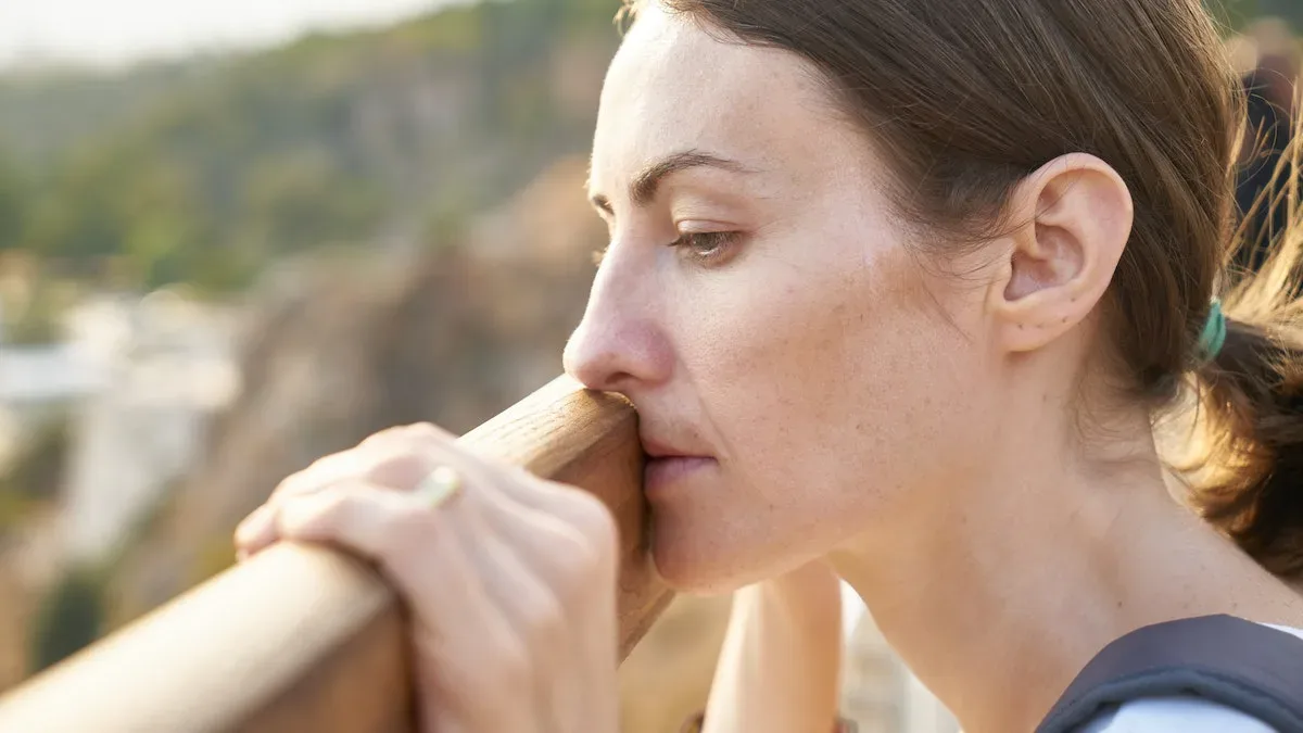 A lady absorbed in thought while holding a fence pole
