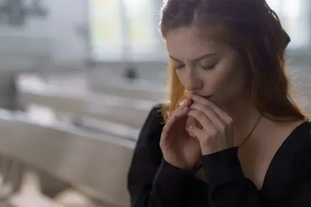 A photo of a young lady praying with hands together and eyes closed